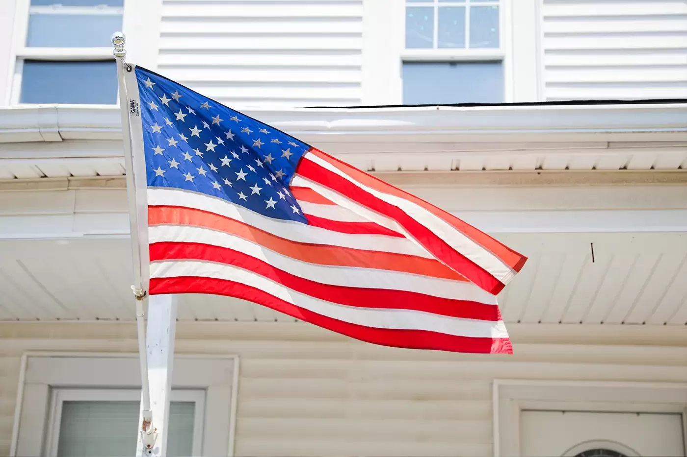Photo of the American flag displayed in front of a house.